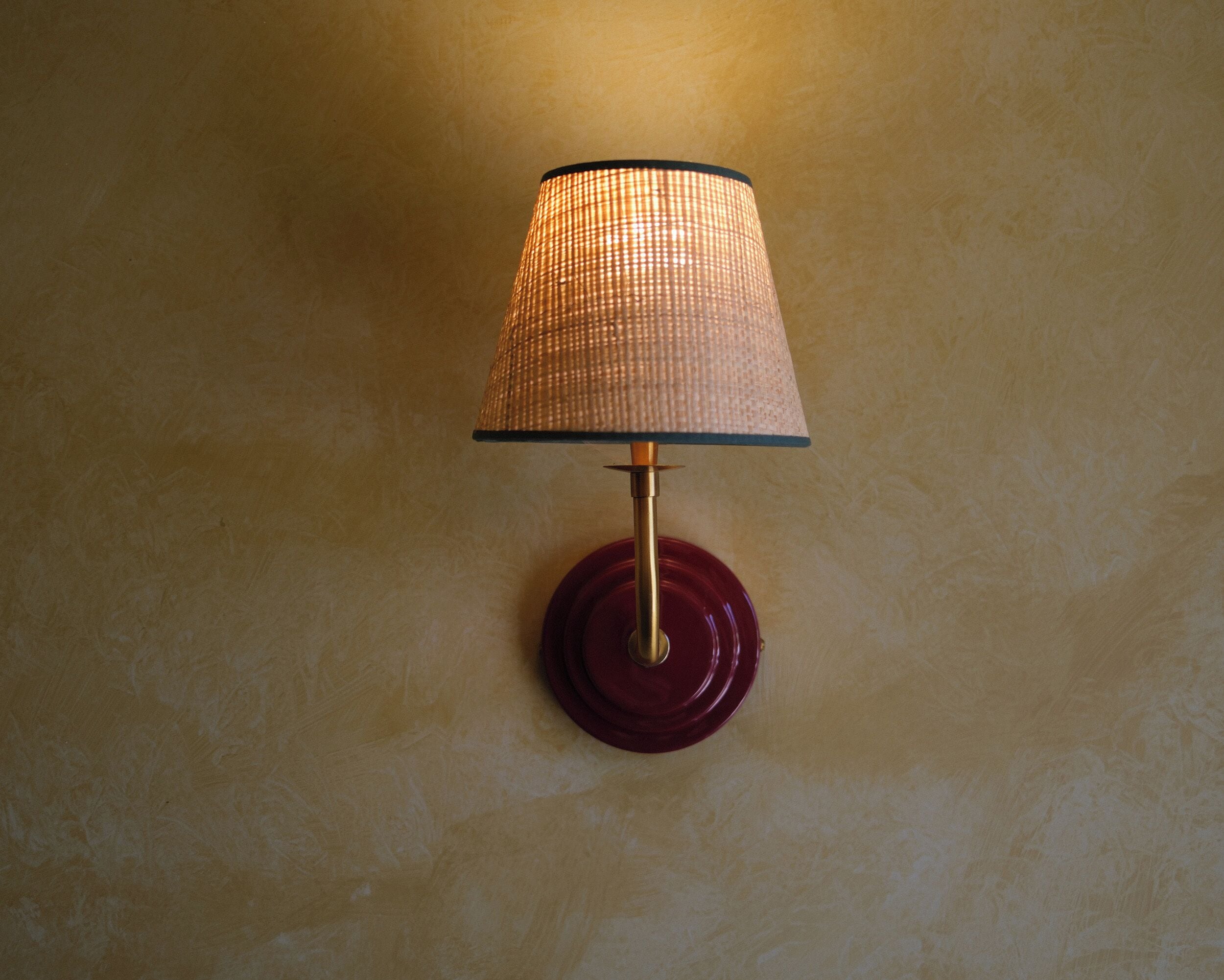 Una lámpara de pared con pantalla estampada de cuadros y base redonda.