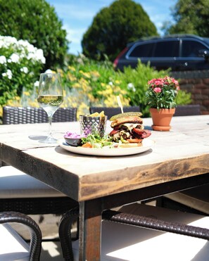 A dining table with a plate of food, a glass of wine, and a potted plant.