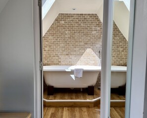 A modern bathroom with a freestanding bathtub, a shower area, and a brick-patterned wall.