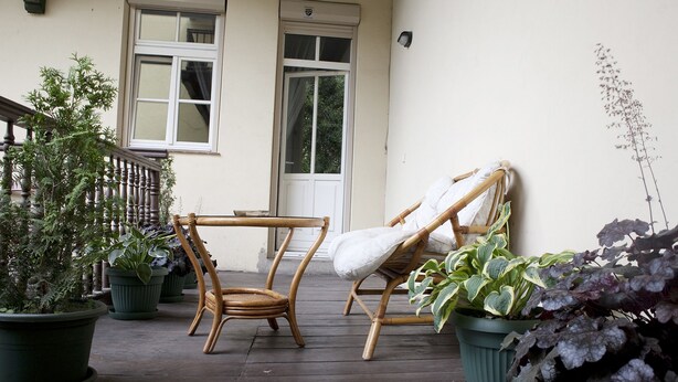 A wooden deck with two wicker chairs and potted plants.