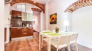 A modern kitchen with wooden cabinets, a brick arch, and a dining area with a table and chairs.
