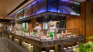 A buffet setup with chefs serving food, a marble counter, and a modern interior design.