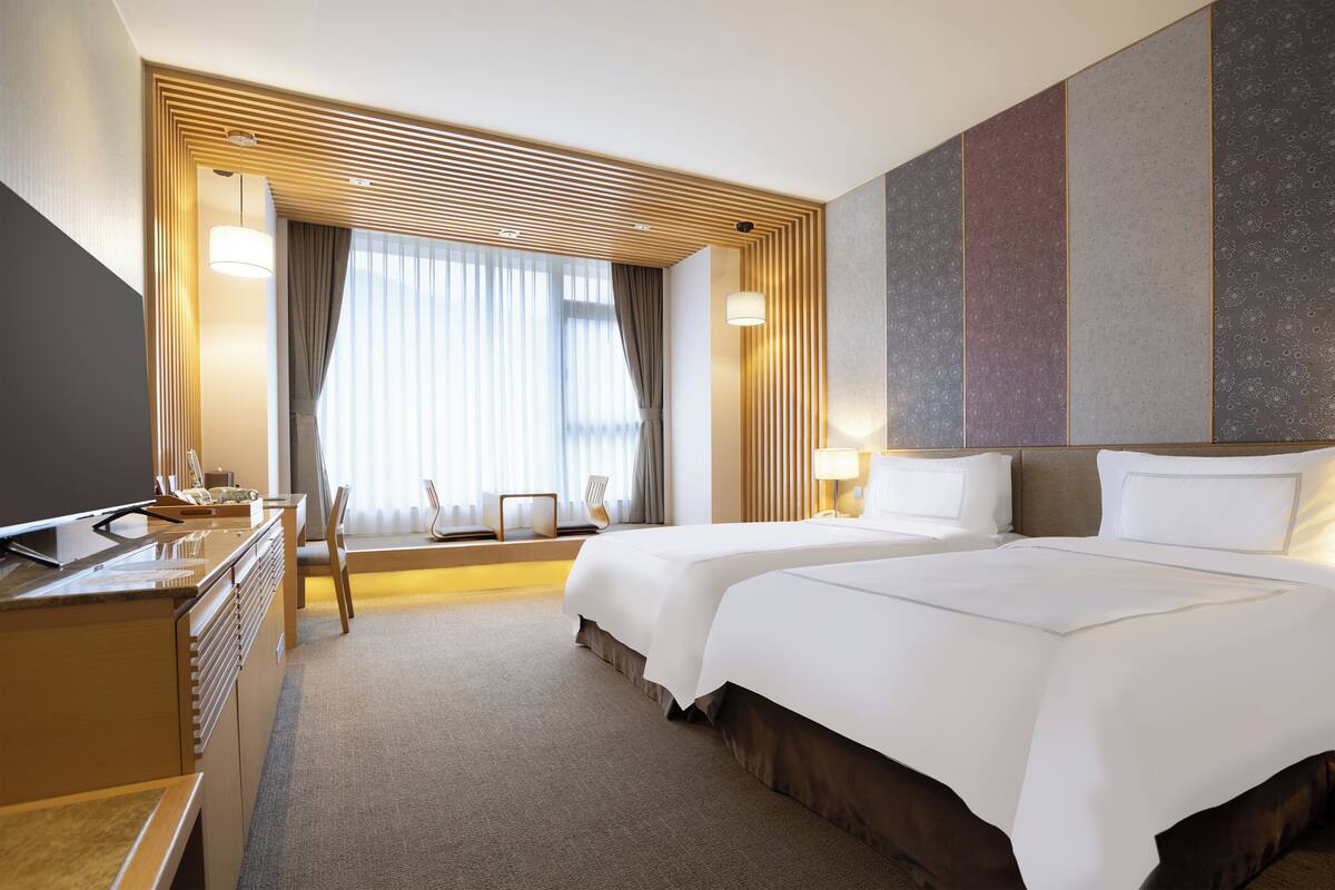 Ett hotellrum med två sängar, ett skrivbord och en stol.