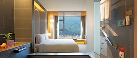 Habitación de hotel con cama, baño con toallero, una planta y vista a la montaña.