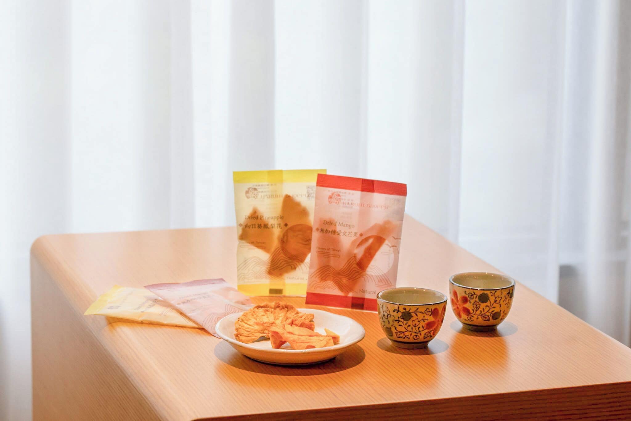Ett träbord med en tallrik torkade snacks, två koppar och informationsbroschyrer.