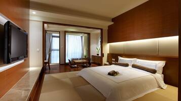 A hotel room with a large bed, a flat-screen TV mounted on the wall, a wooden headboard, and a view of the outside through a glass door.
