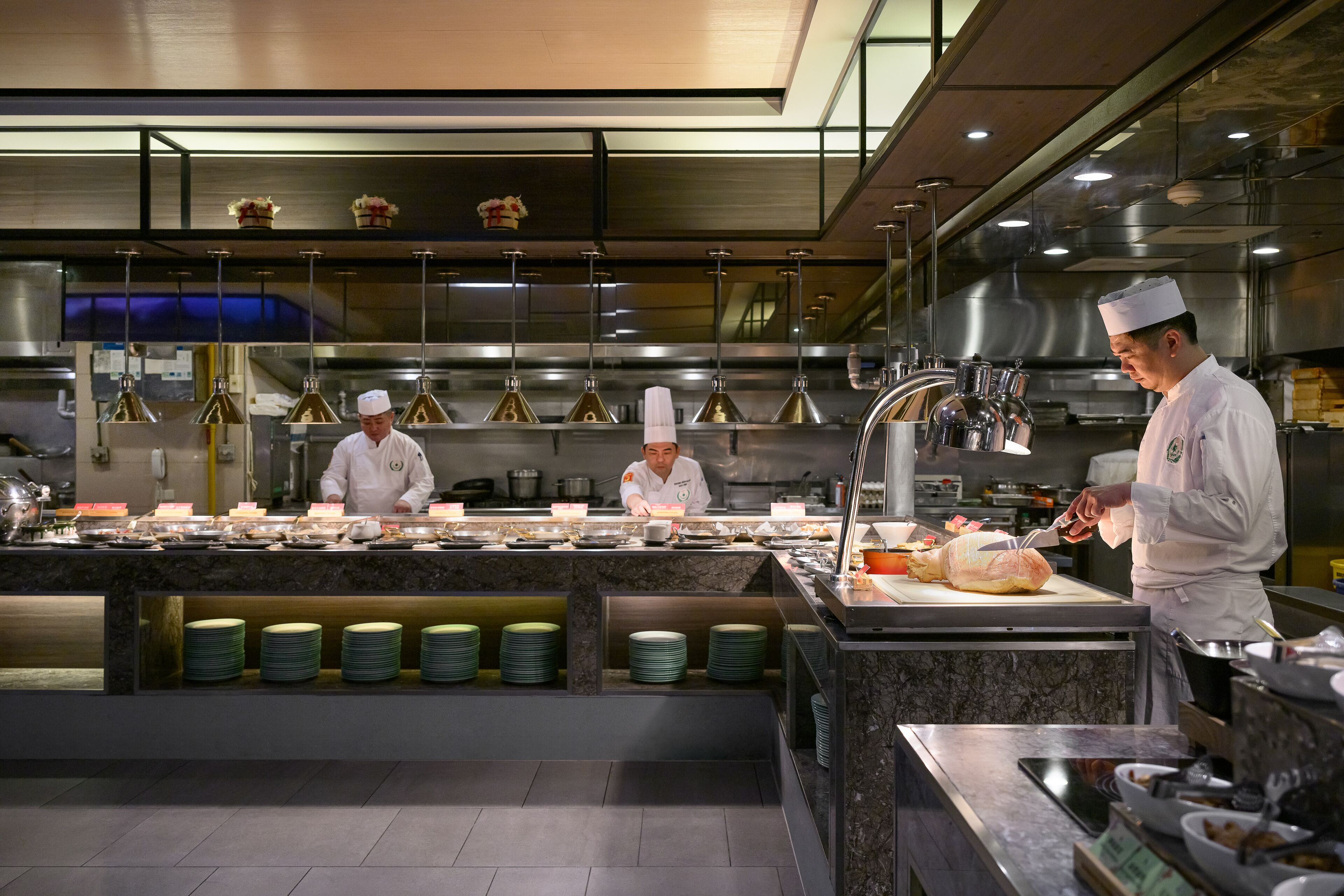 A professional kitchen with chefs preparing food, stainless steel appliances, and neatly arranged plates.