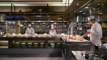 A professional kitchen with chefs preparing food, stainless steel appliances, and neatly arranged plates.