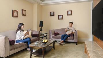 A living room with two sofas, a coffee table with fruit, and a TV.
