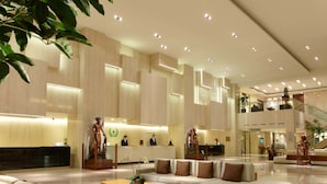 A spacious lobby with a reception desk, seating area, and a staircase.