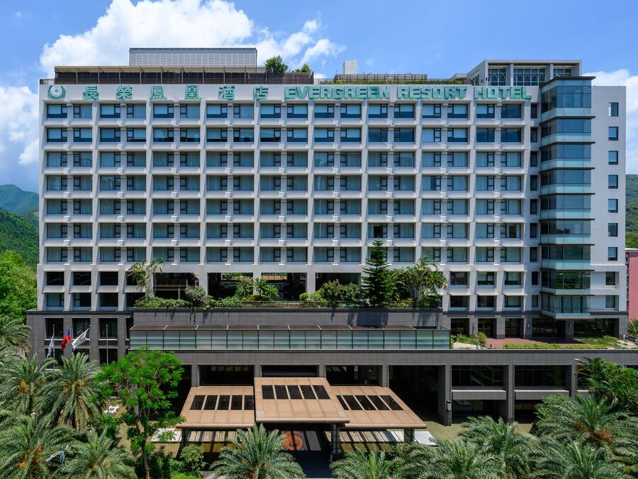 A multi-story hotel with a modern facade, large windows, and a rooftop garden.