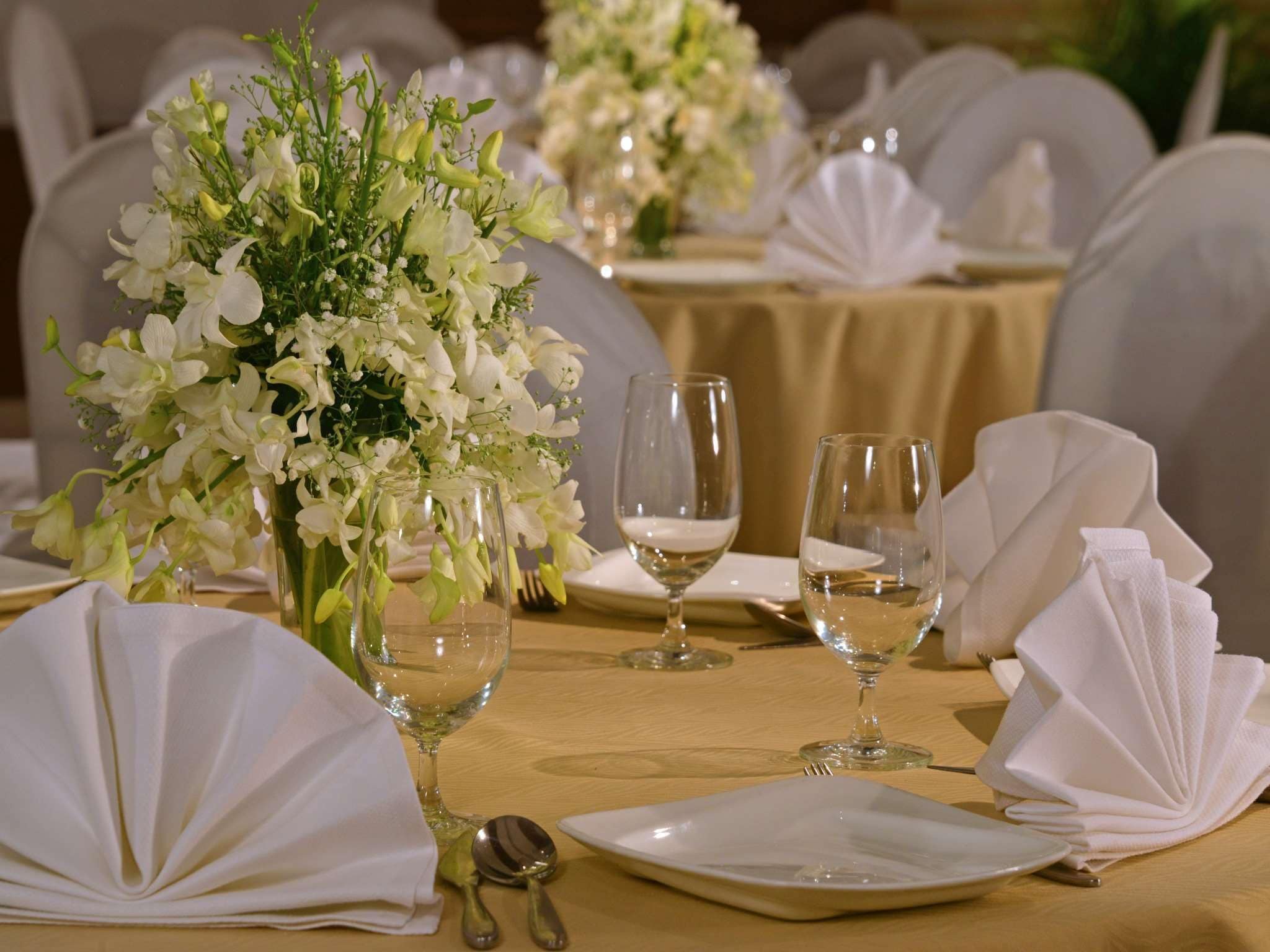 A table set for a formal event with white flowers, wine glasses, and folded napkins.