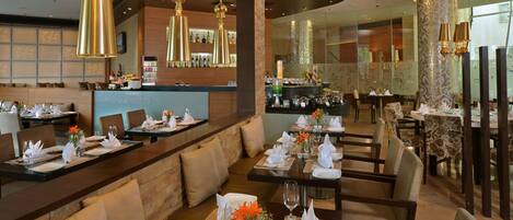 A restaurant with multiple dining tables set for guests, a bar area with bottles, and a modern interior design.