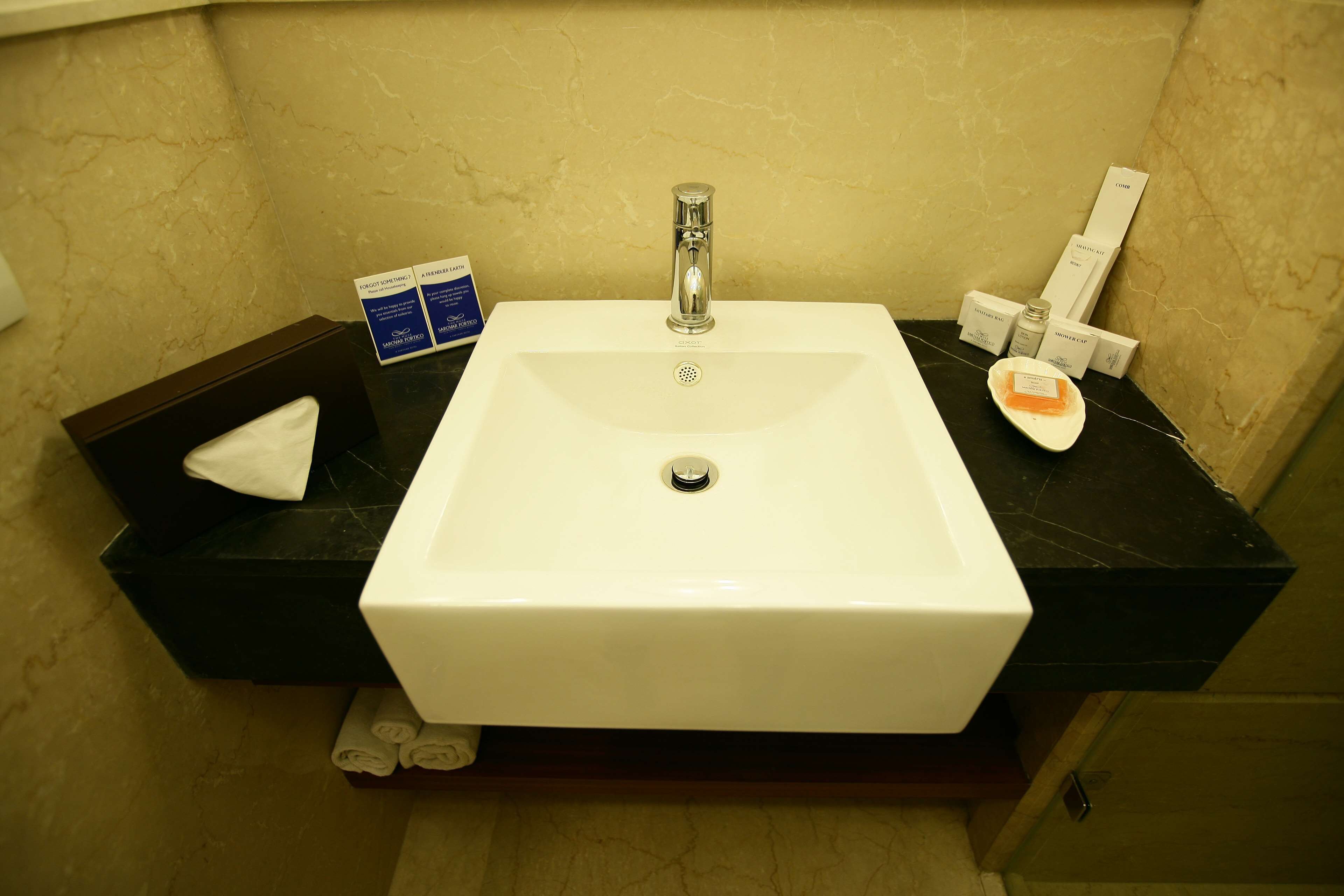 A bathroom with a white sink, a mirror, and toiletries on the counter.