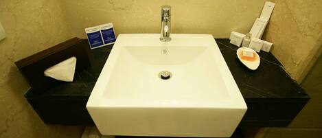 Un baño con lavamanos blanco, un espejo y artículos de aseo en la encimera.
