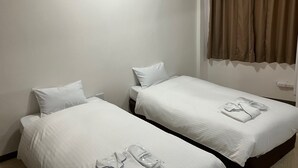 A hotel room with two single beds, a window with curtains, and an air conditioning unit. - Enagic Okinawa International Plaza Hotel (Naha)