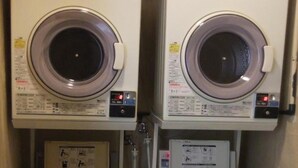 Two stacked front-loading washing machines with control panels and a smaller dryer below each. - Enagic Okinawa International Plaza Hotel (Naha)