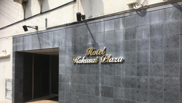 The exterior of Hotel Kokusai Plaza with a modern design, featuring a prominent entrance and a sign with the hotel's name. - Enagic Okinawa International Plaza Hotel (Naha)