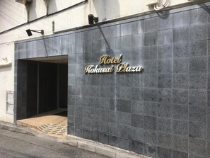 Das Hotel Kokusai Plaza mit moderner Gestaltung, darunter ein markanter Eingangsbereich und eine Beschilderung mit dem Namen des Hotels.