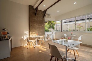 Uma área de refeições moderna com uma mesa grande, cadeiras brancas e uma parede de pedra rústica.