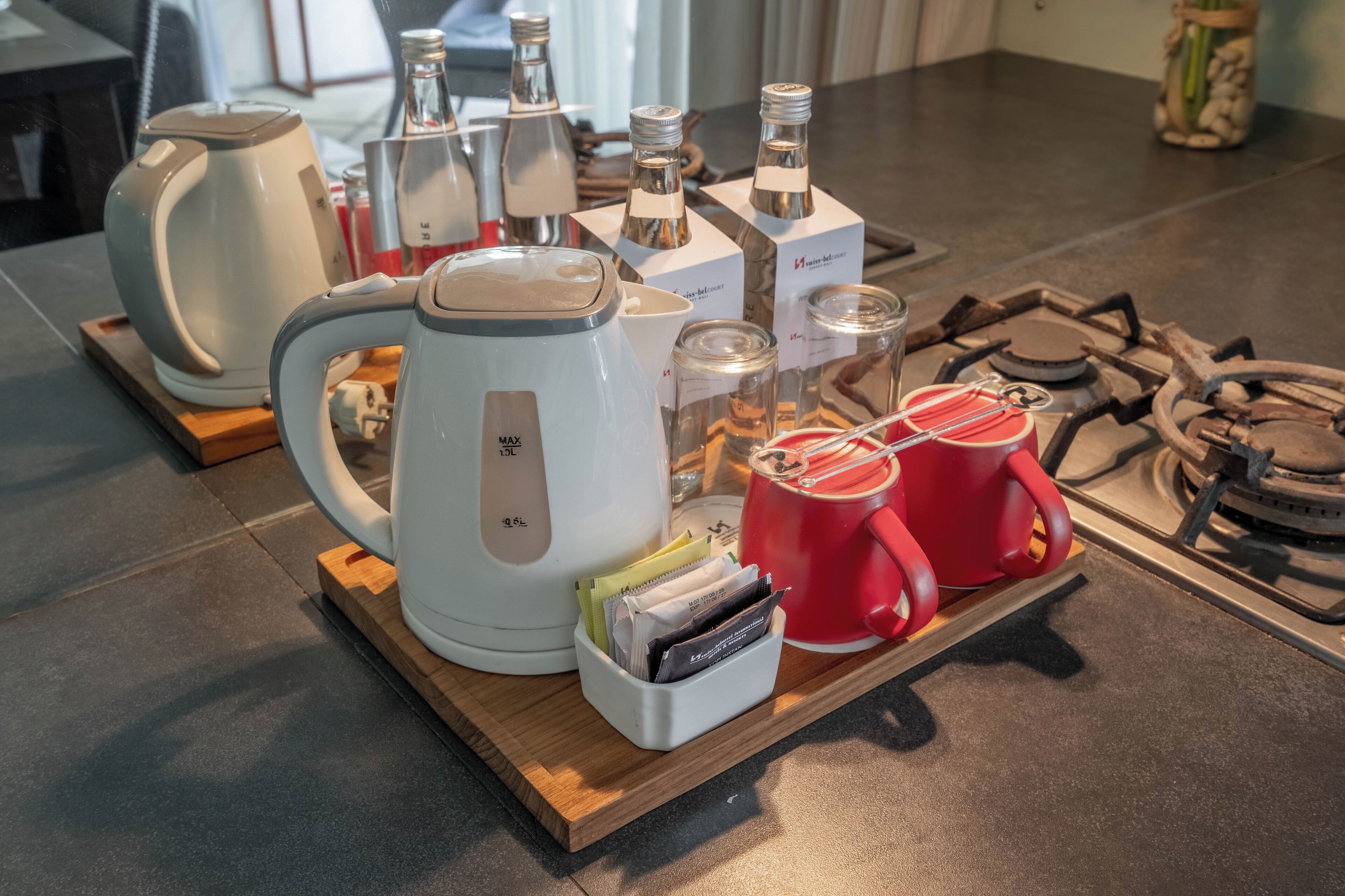 Un coin cuisine équipé d’une machine à café, de bouilloires et d’un plateau contenant des tasses et des sachets de thé.