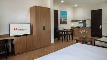 Quarto de hotel com cama, escrivaninha, guarda-roupa, área de refeições e cozinha.
