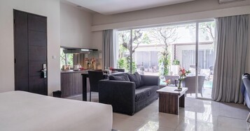 Quarto de hotel moderno com uma cama grande, um sofá, uma mesa de jantar e uma cozinha.