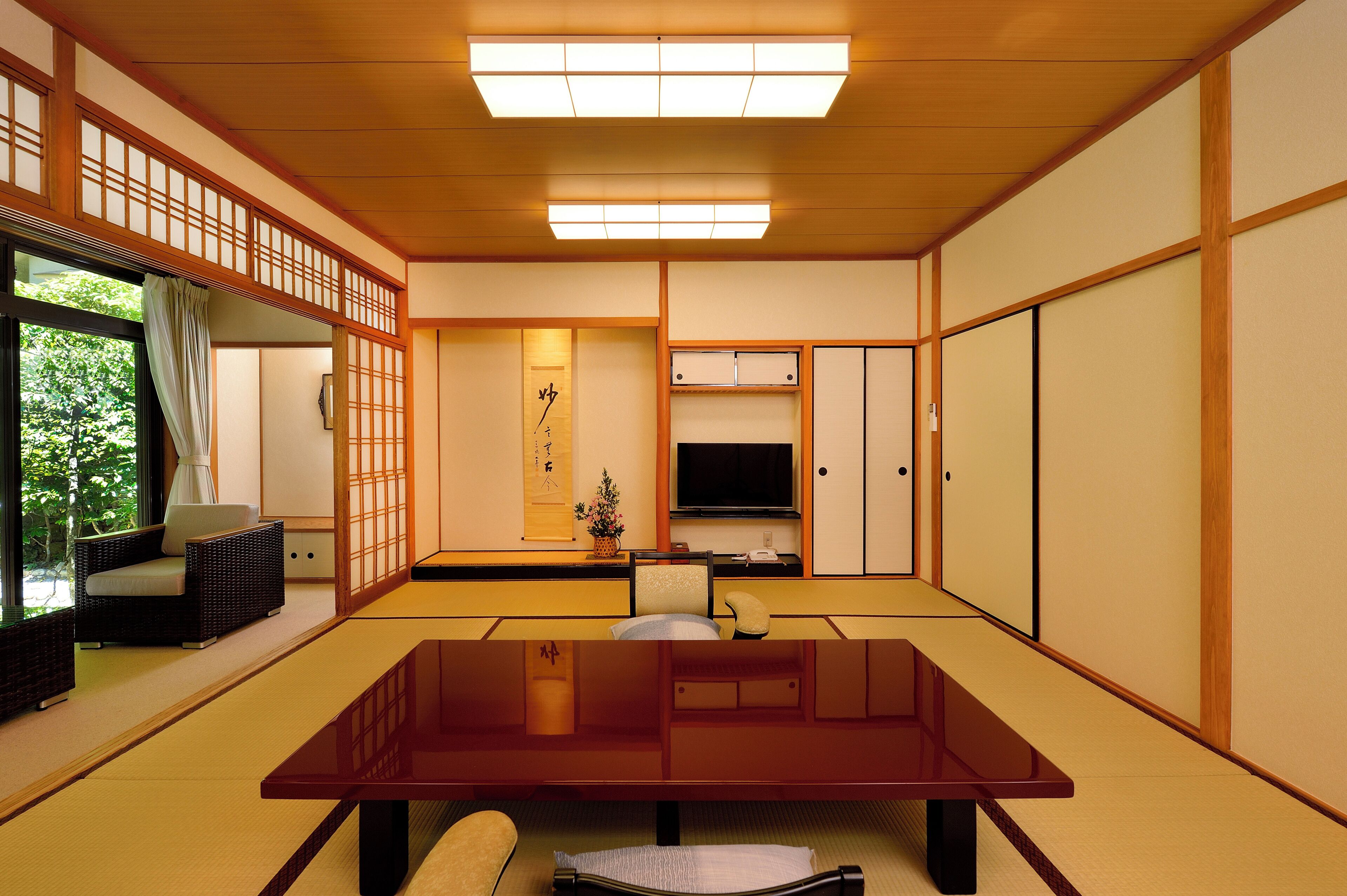 A traditional Japanese-style room with tatami flooring, a low table, a sofa, and sliding doors.