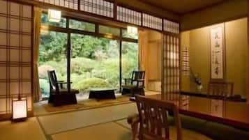 A traditional Japanese room with tatami flooring, sliding doors, and a view of a lush garden.