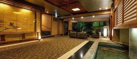 A traditional interior with a koi pond, wooden flooring, and a view of the outdoors.