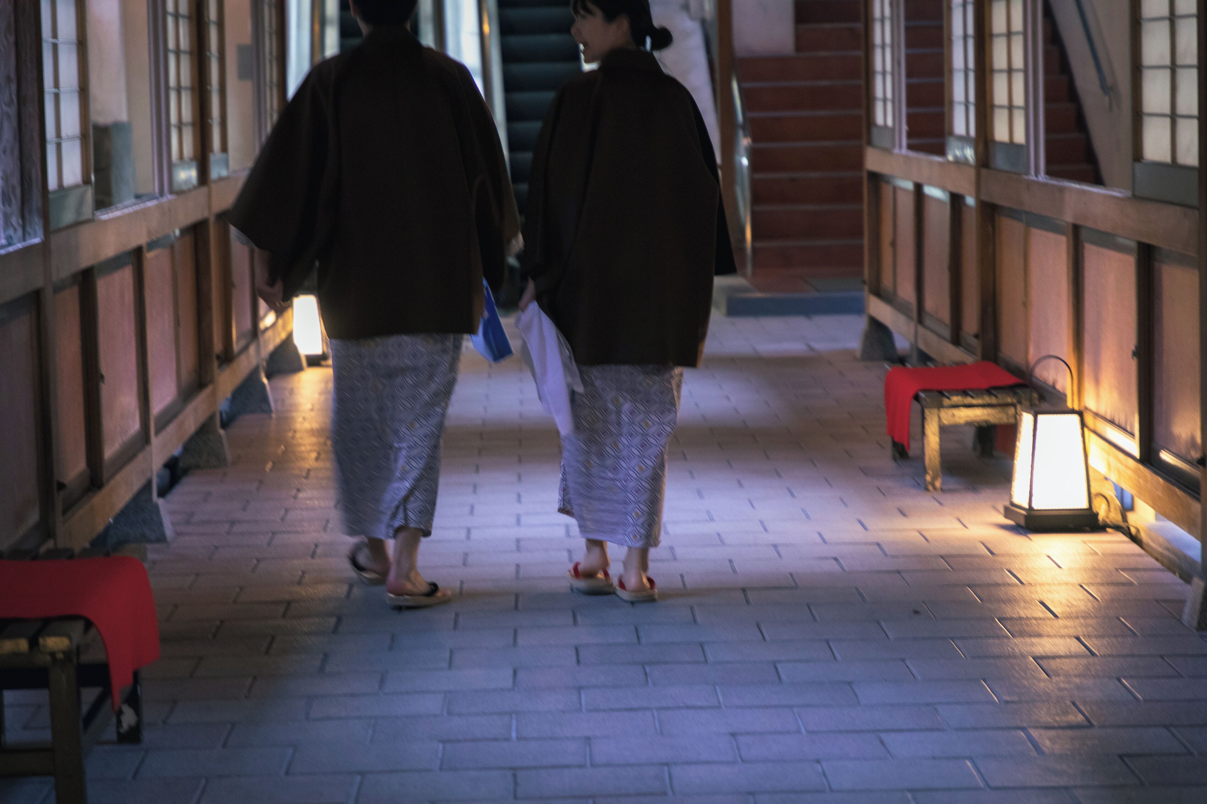 A corridor with wooden railings, tiled flooring, and traditional lanterns.