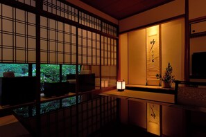 A traditional Japanese room with tatami flooring, a low table, and a sliding door with a view of greenery outside. - Arima Onsen Gekkoen Yugetsusanso (Kobe)