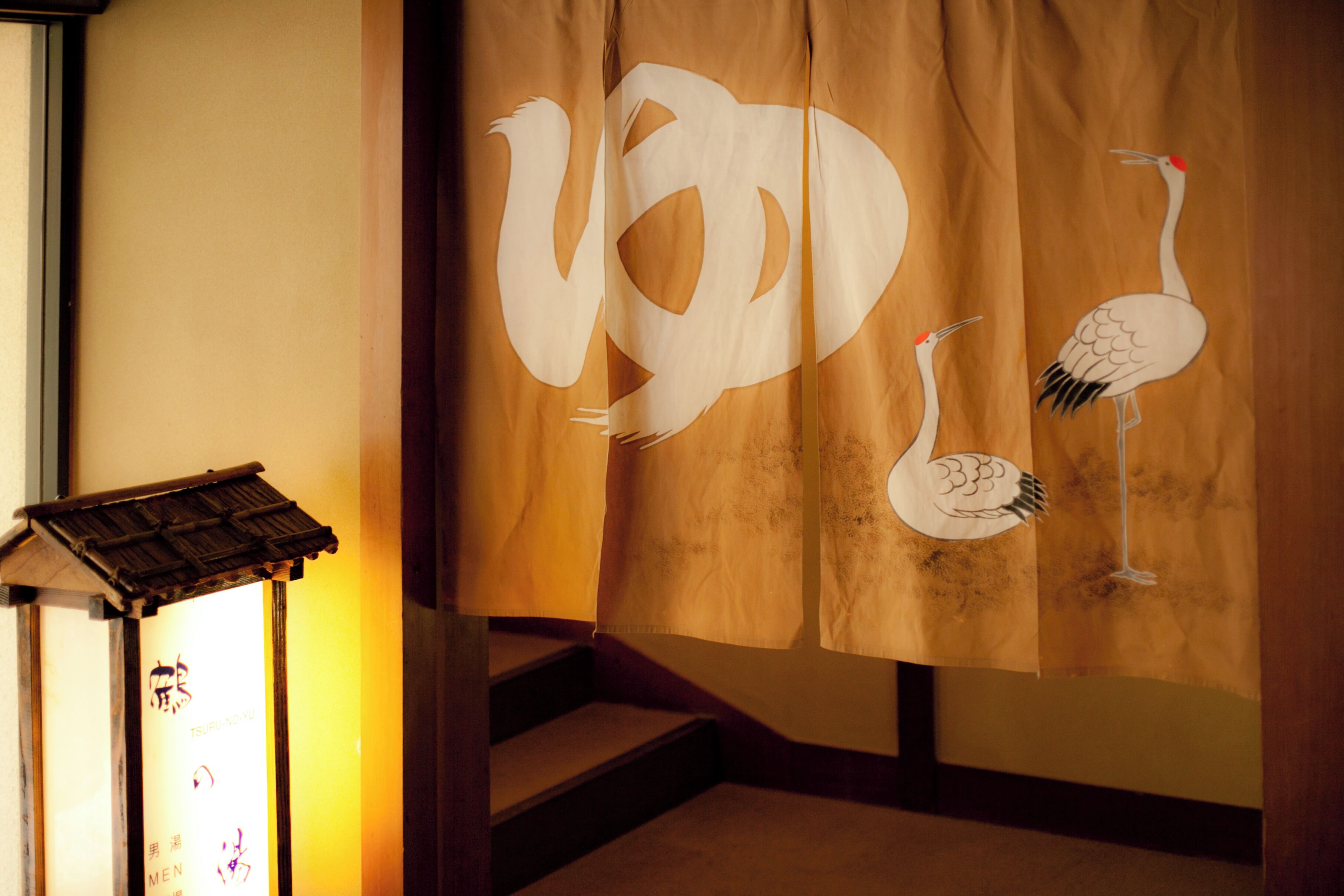 A traditional Japanese interior with a tatami mat floor, a shoji screen with crane designs, and a small shrine with a roof.