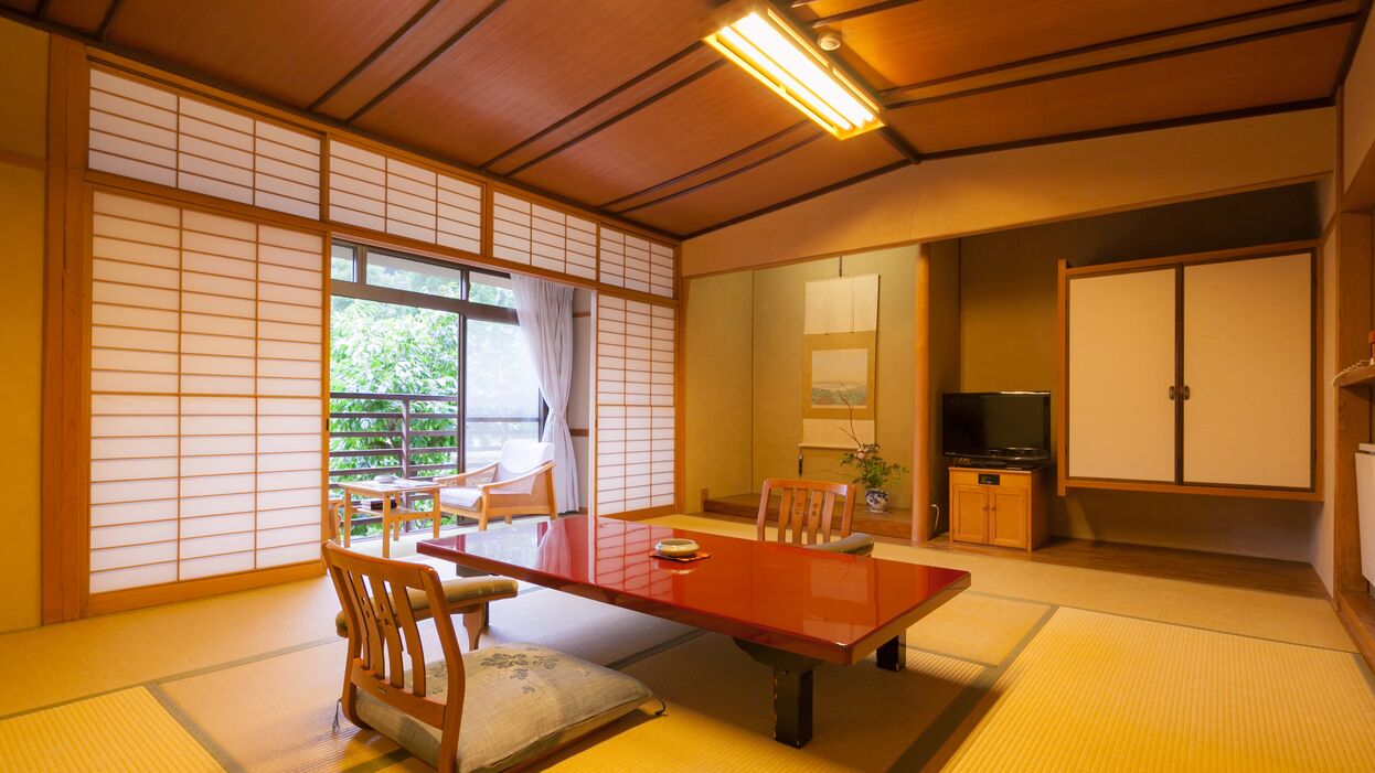 Une pièce de style japonais traditionnel, avec un sol recouvert de tatamis, une petite table en bois et des portes coulissantes.
