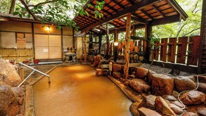 Un onsen japonés tradicional con estructura de madera, un baño de aguas termales y una cerca de madera.