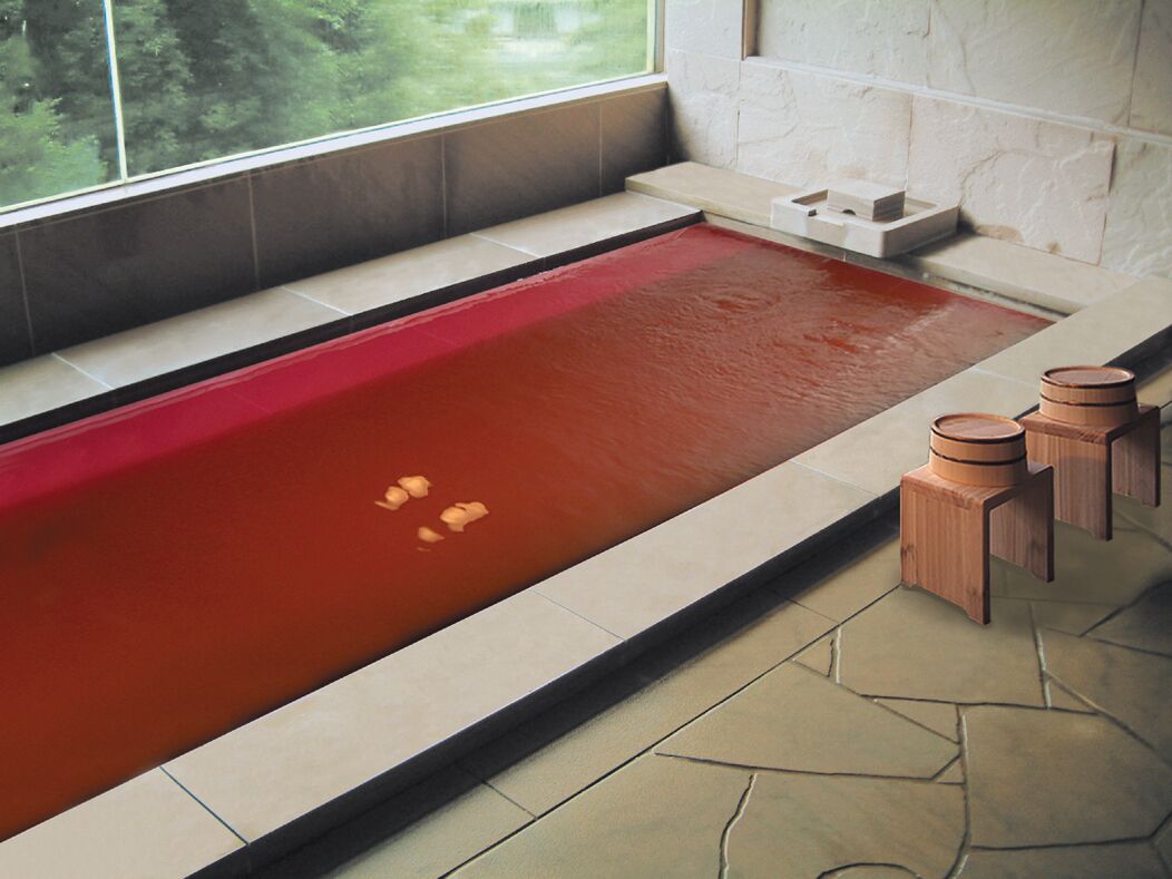 A spa area with a hot tub, stone tiles, and wooden stools.