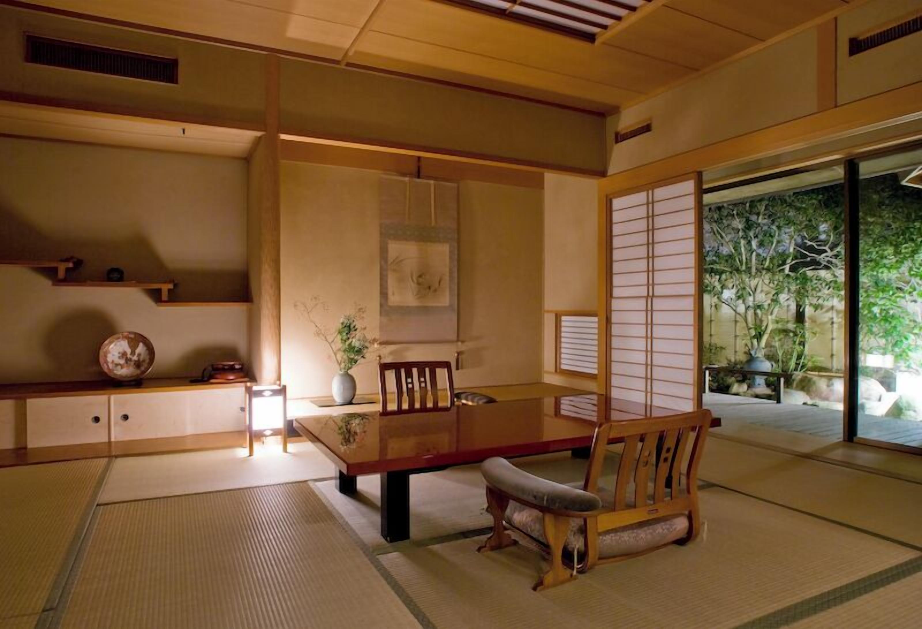 Een traditionele Japanse kamer met tatami vloerbedekking, een lage houten tafel, een zacht bankje en verschuifbare shoji schermen.