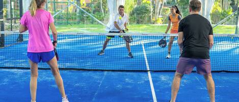 Un court de tennis où des joueurs sont en pleine action, entouré d’un filet et d’une clôture.