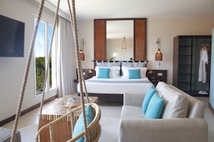 A hotel room with a large bed, a sofa, a small table, and a hanging chair.