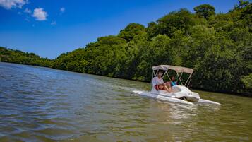 Un bote con toldo en un río rodeado de densa vegetación verde.