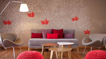 Una sala de estar moderna con un sofá gris, cojines rojos, dos sillones grises, una mesa de centro de madera y una lámpara de pie.