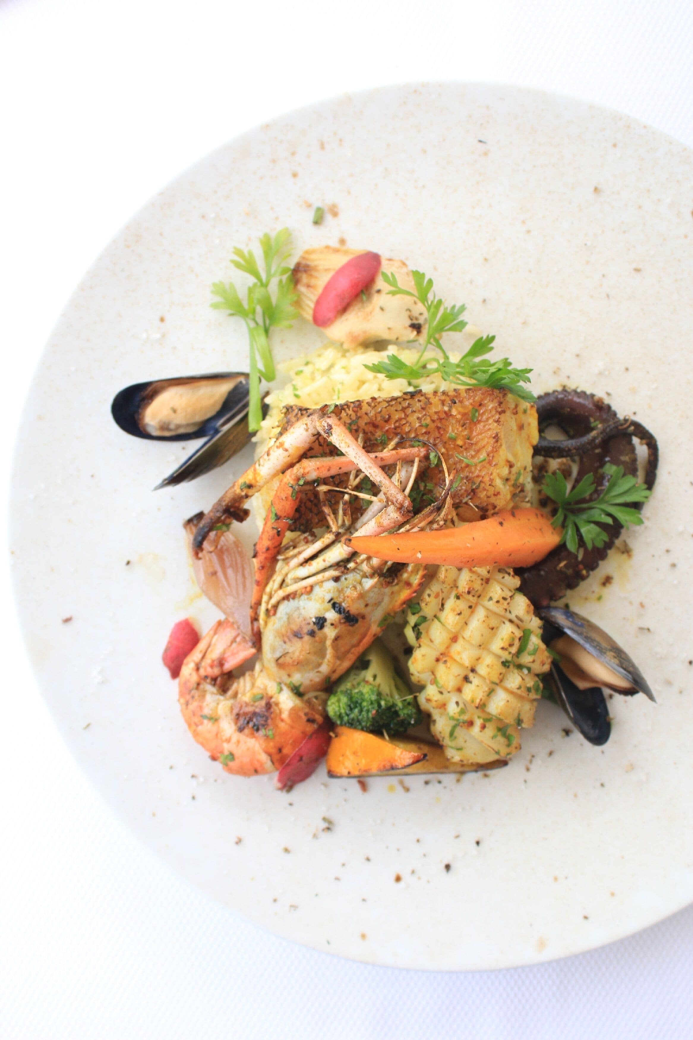 A seafood dish with mussels, shrimp, and vegetables on a plate.