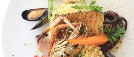 A seafood dish with mussels, shrimp, and vegetables on a plate.