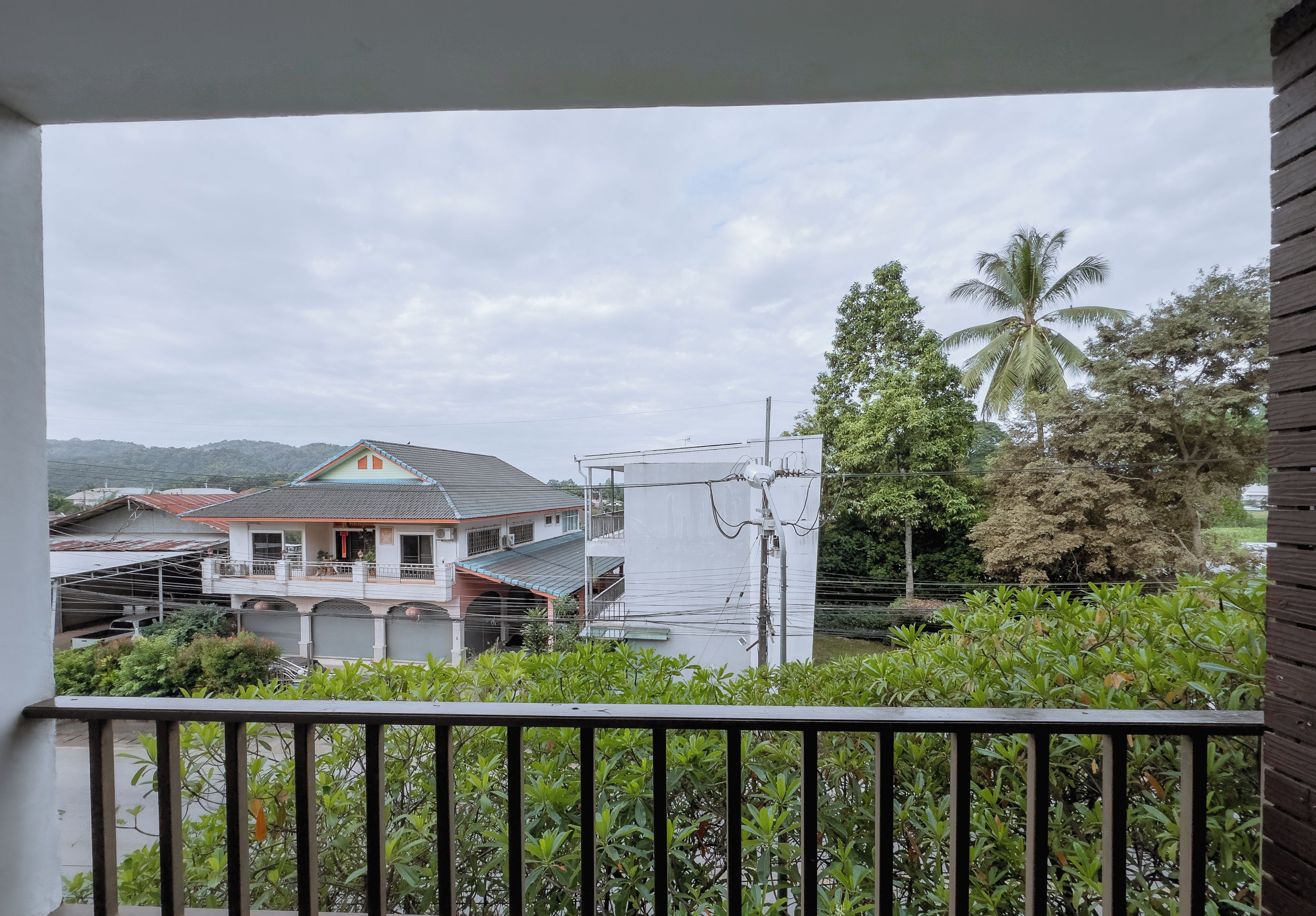 A residential area with a house featuring a balcony, a utility pole, and a palm tree.