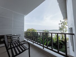 Un balcón con vistas a un lago y montañas, una mesa y una silla.