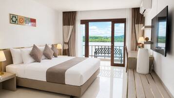 A hotel room with a bed, bedside tables, a TV, a desk, and a balcony with a view.