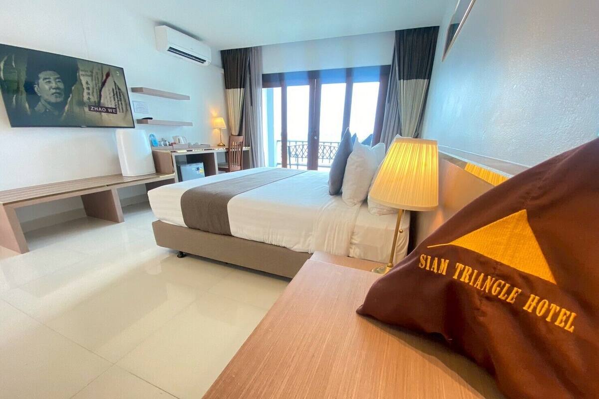 Una habitación de hotel con una cama grande, un escritorio, un televisor y una ventana con cortinas.