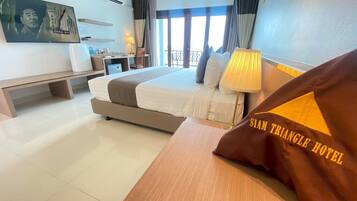 A hotel room with a large bed, a desk, a TV, and a window with curtains.