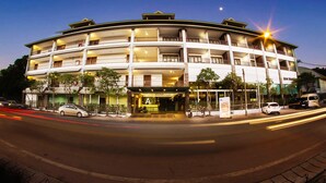 Un hotel de varios pisos con entrada central, balcones en cada planta y una fachada bien iluminada.