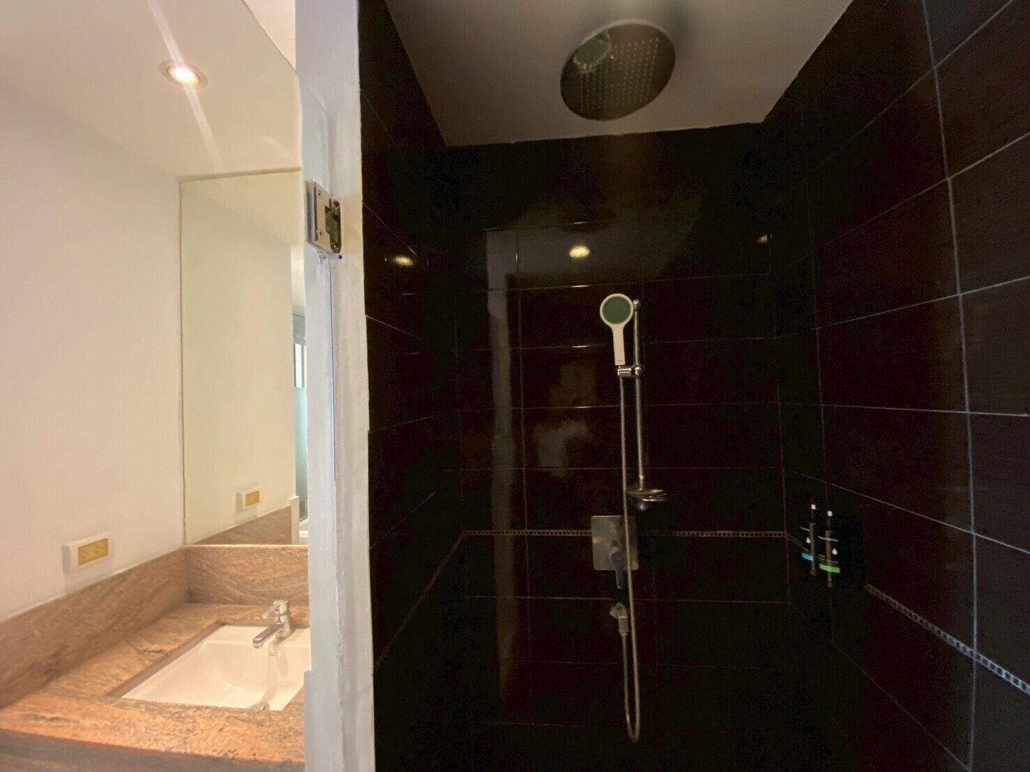 Un baño moderno con ducha de vidrio, un lavamanos y un espejo.
